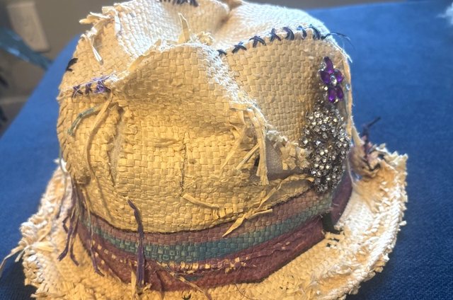 Distressed straw hat with stitched details, multicolor band, and jeweled brooch