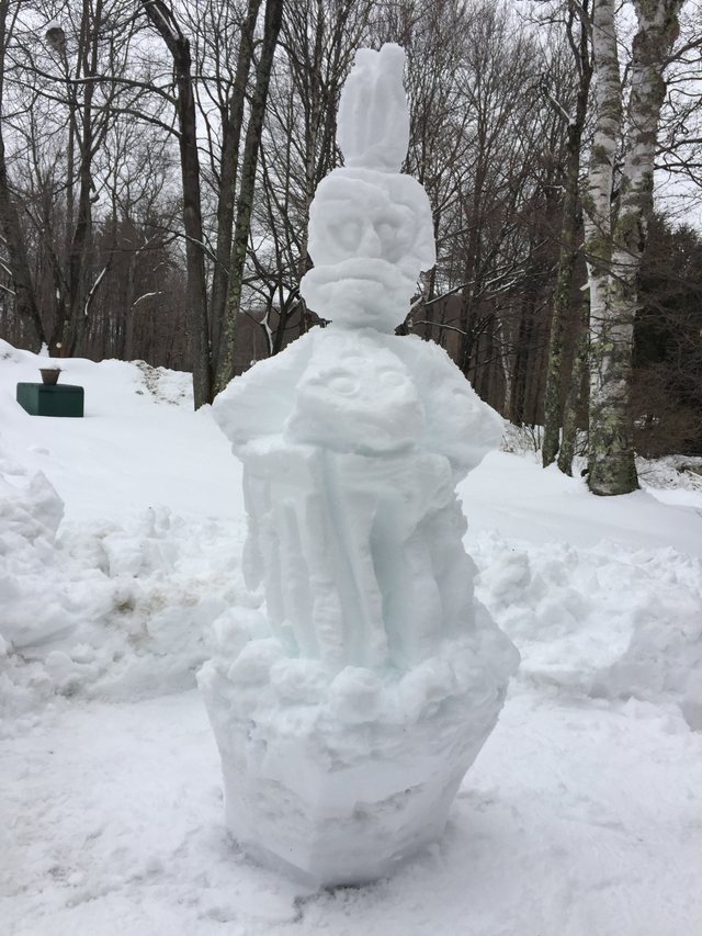 Tall figurative snow sculpture in a winter woodland